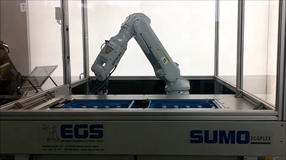 Weißer Roboterarm bewegt Werkstücke